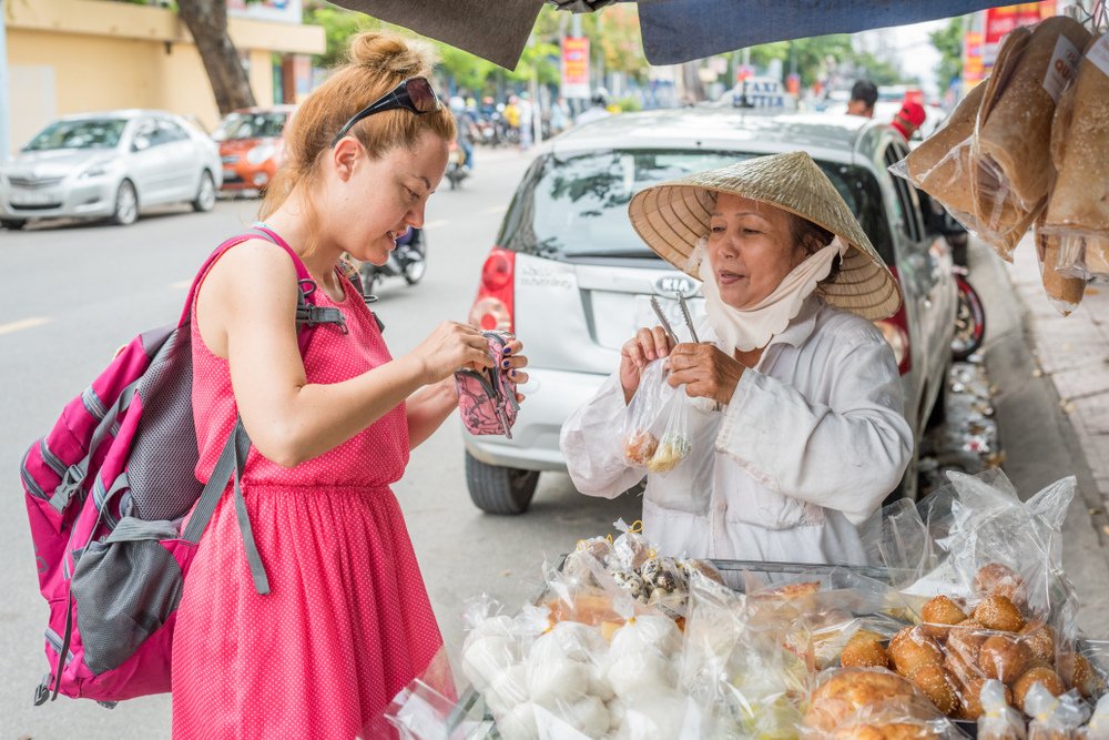 a woman is paying for a street vendor